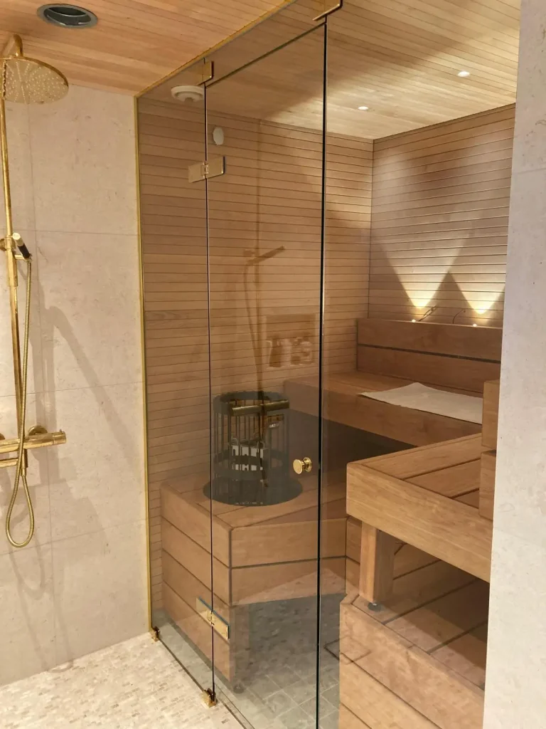 Avaran ja rennon tyylinen sauna, puulauteet, lasiset ovet joista näkee läpi.